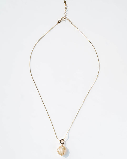 Gold necklace with a shell pendant on a light gray background