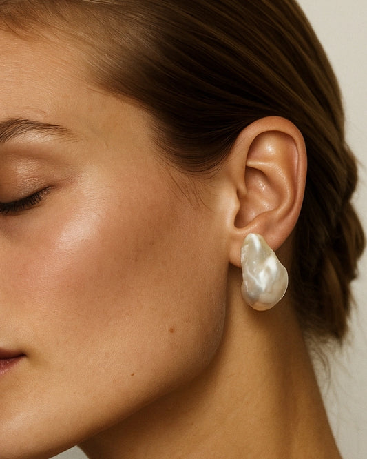Close-up of a person wearing pearl earring with a neutral background